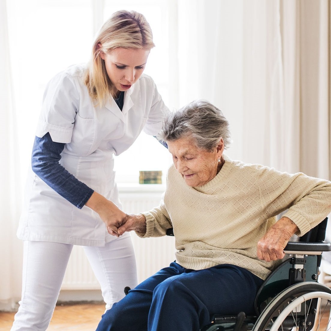 Home health professional helping a senior woman rise from her wheelchair