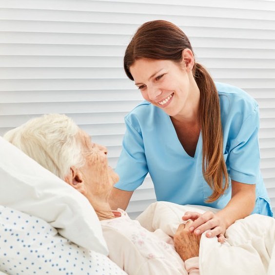 Private duty nurse reassuring an older woman in bed